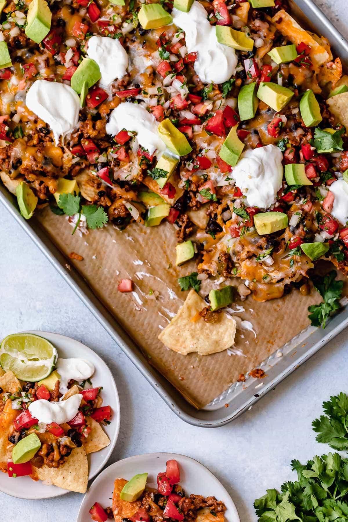 Easy Nachos - layered with seasoned beef and black beans, melty cheese, avocado and sour cream. SO GOOD! #nachos #sheetpan #beef #blackbeans #dinner #recipe Easy nachos recipe.