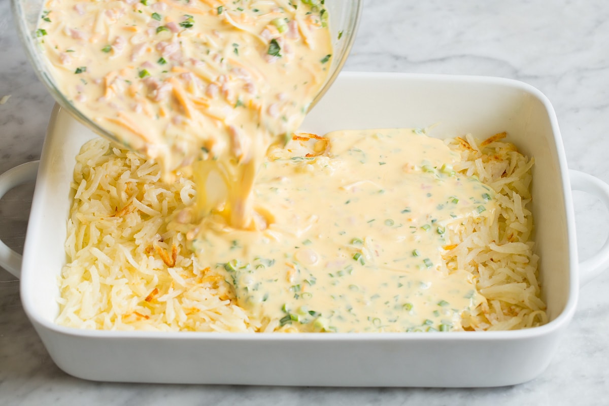 Pouring breakfast casserole mixture into casserole dish.