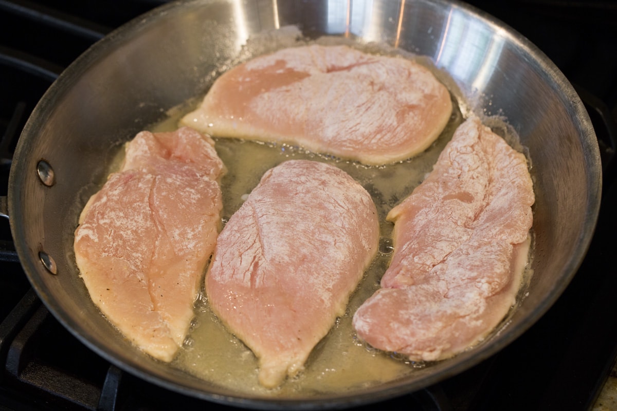 Pan searing four chicken pieces.