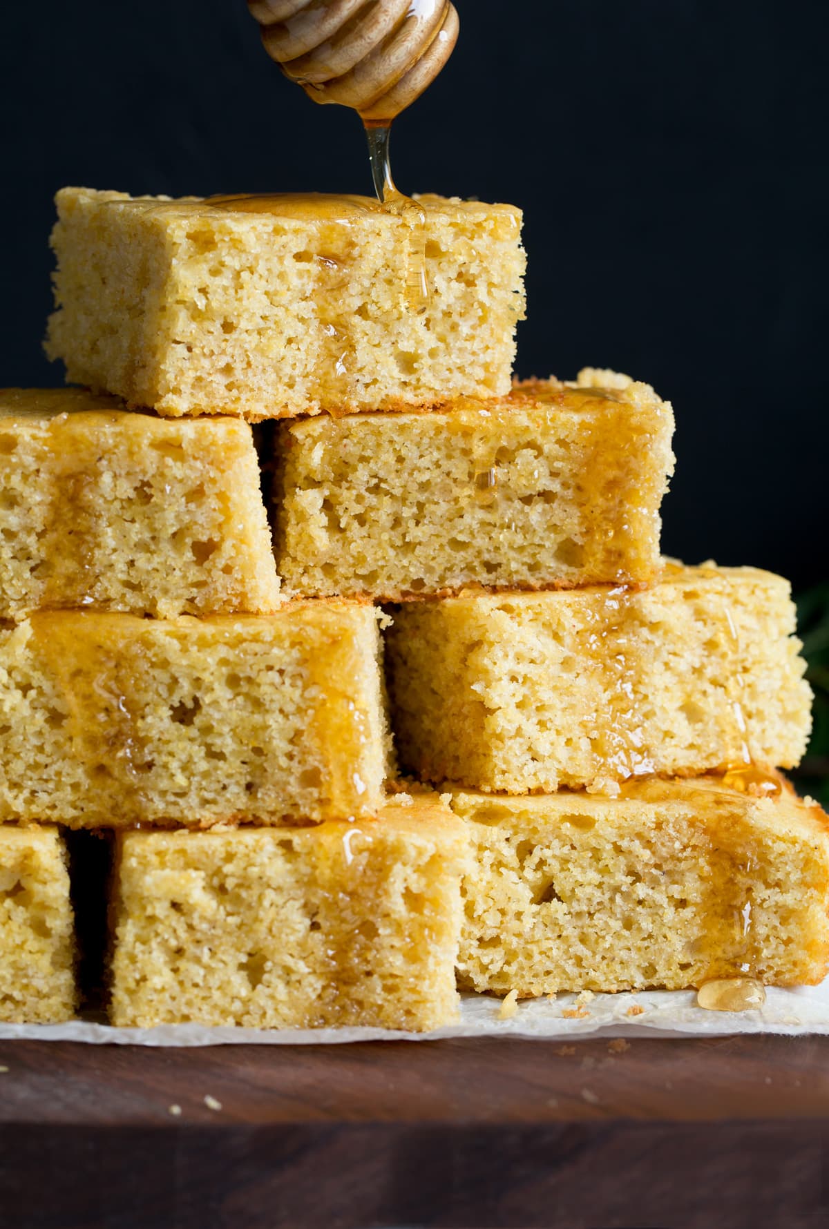 Drizzling honey on a pyramid of homemade cornbread