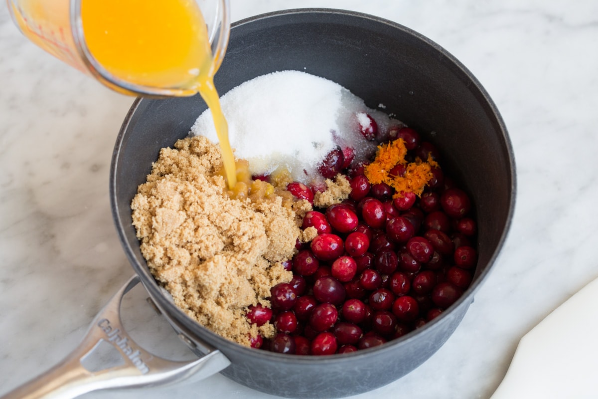 Adding cranberry sauce ingredients to a medium saucepan.