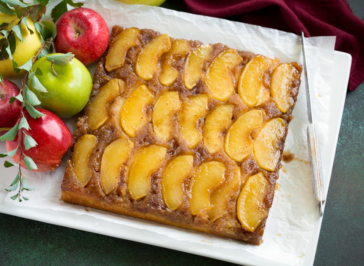 Whole apple upside down cake on a white serving plater.