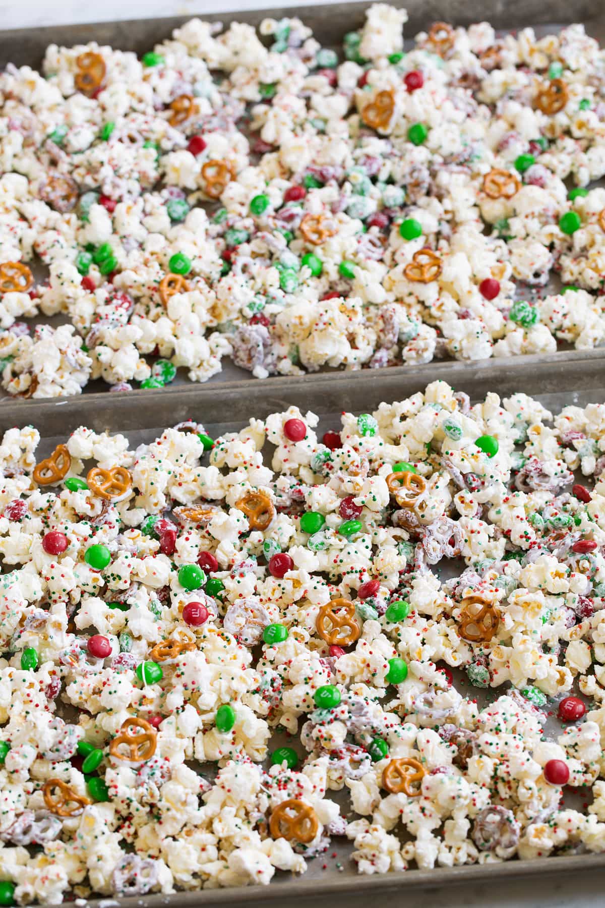 Christmas popcorn treat setting in baking sheets over parchment paper to dry.