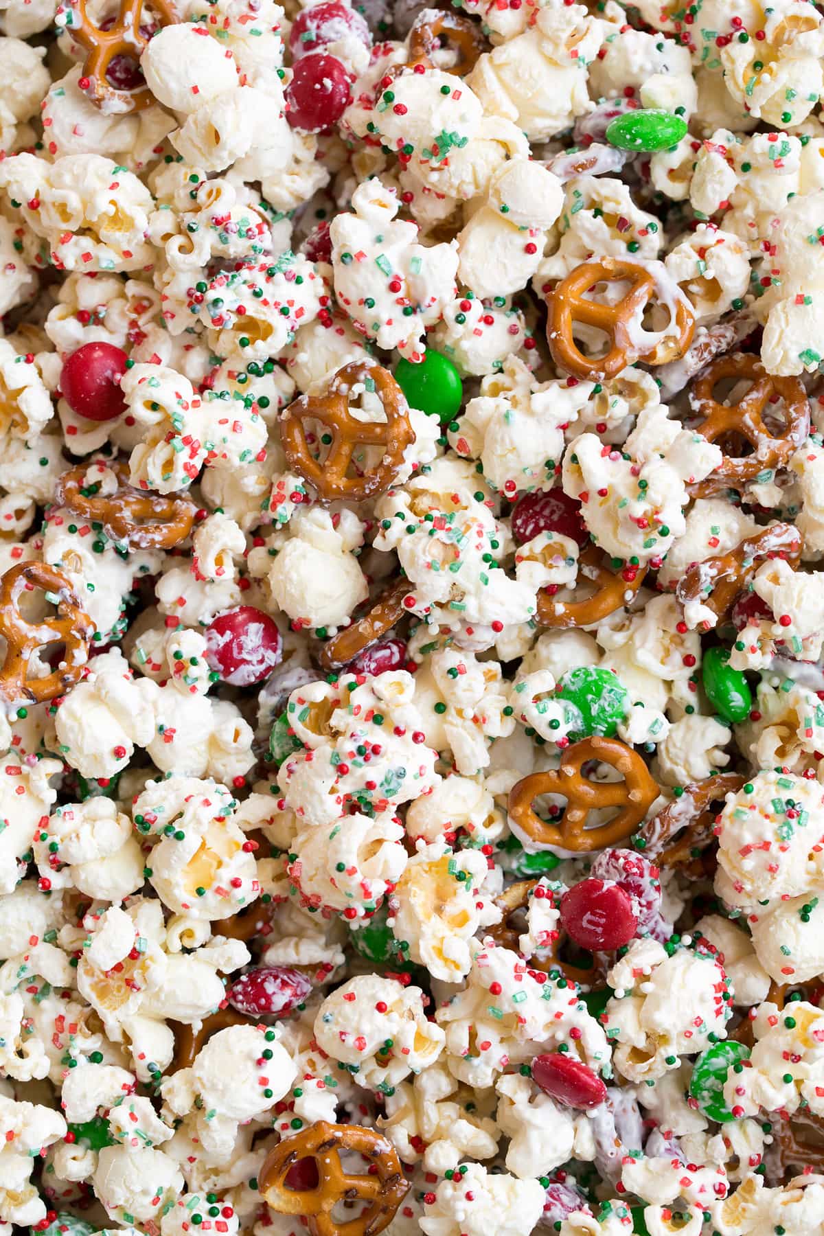 Close up image of white chocolate coated popcorn with pretzels sprinkles and m and m's.