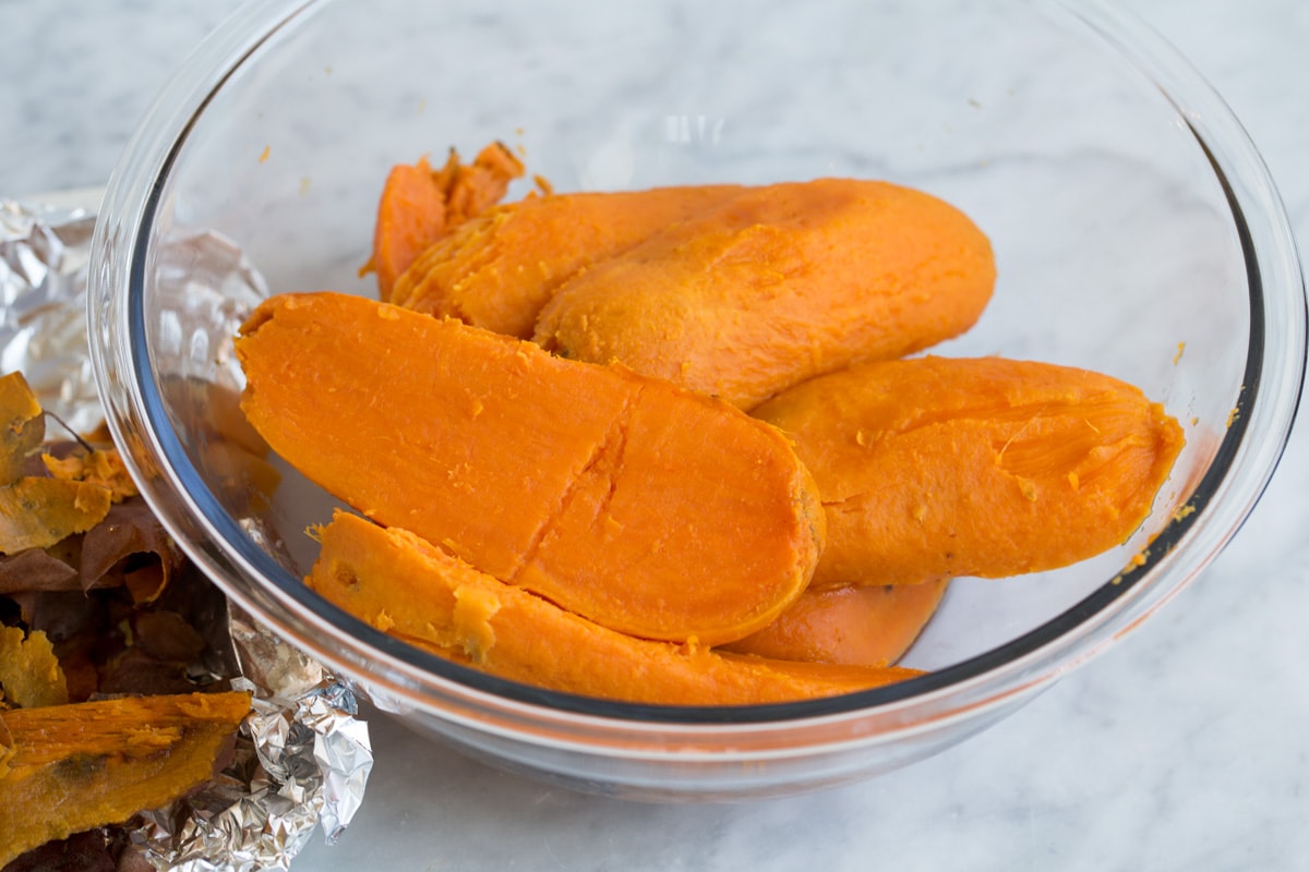 Mashed Sweet Potatoes - one of the best fall side dishes! These really are the best mashed sweet potatoes the secret ingredient is the browned butter! #mashedpotatoes #sweetpotatoes #sidedish #thanksigving Baked skinless sweet potatoes halves in a large glass mixing bowl. Showing how to make mashed sweet potatoes.