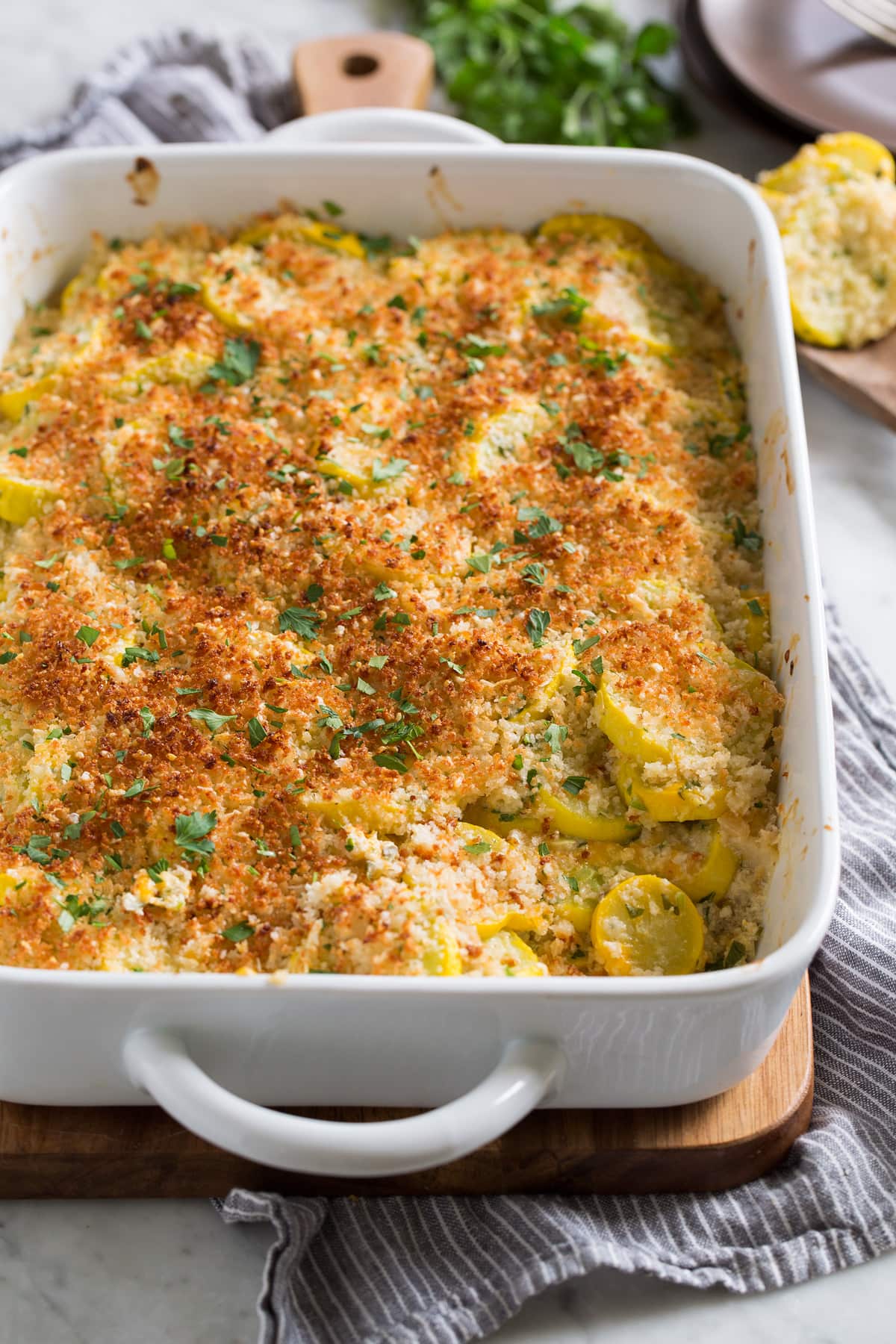 Baked yellow Squash Casserole in a white ceramic baking dish.