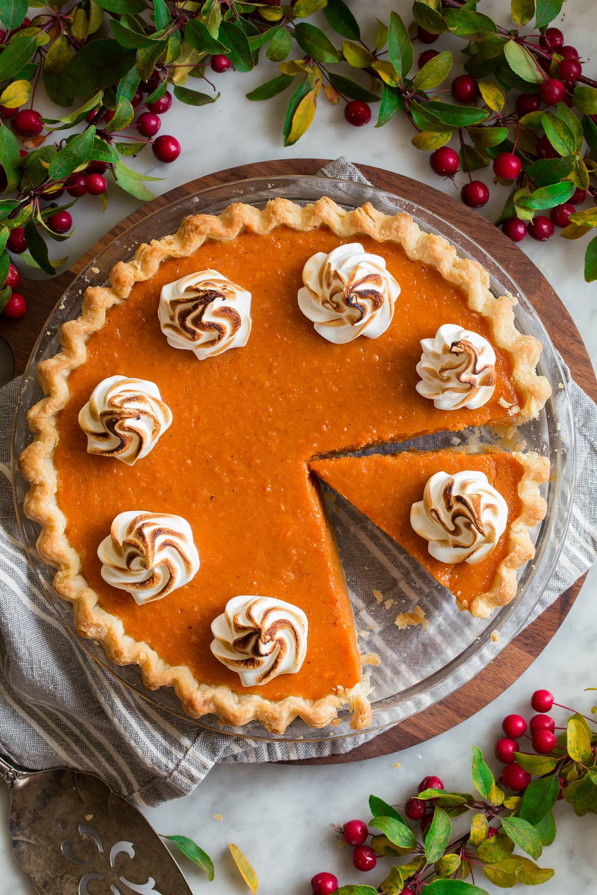 Overhead image of sweet potato pie with a slice cut. Pie is topped with marshmallow swirls.