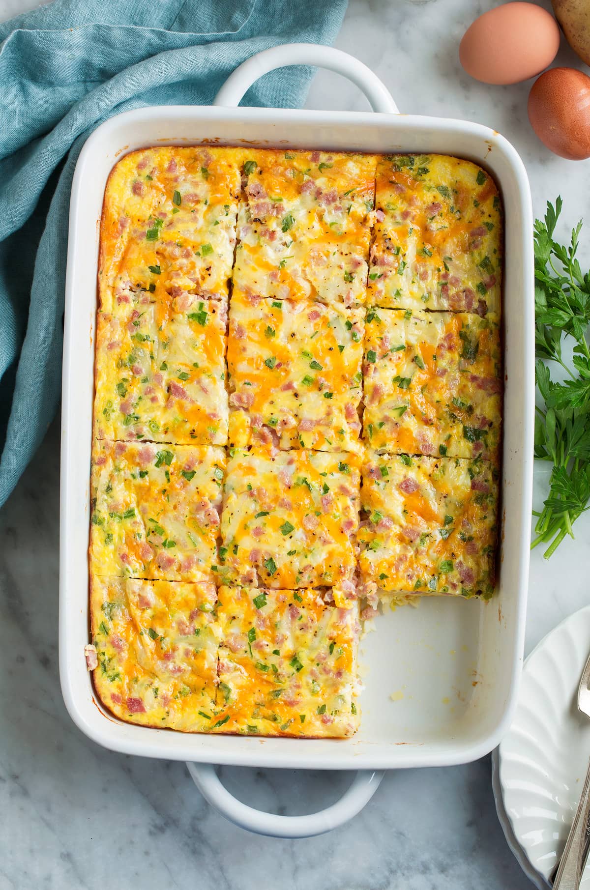 Overhead image of breakfast casserole in a baking dish cut into slices.