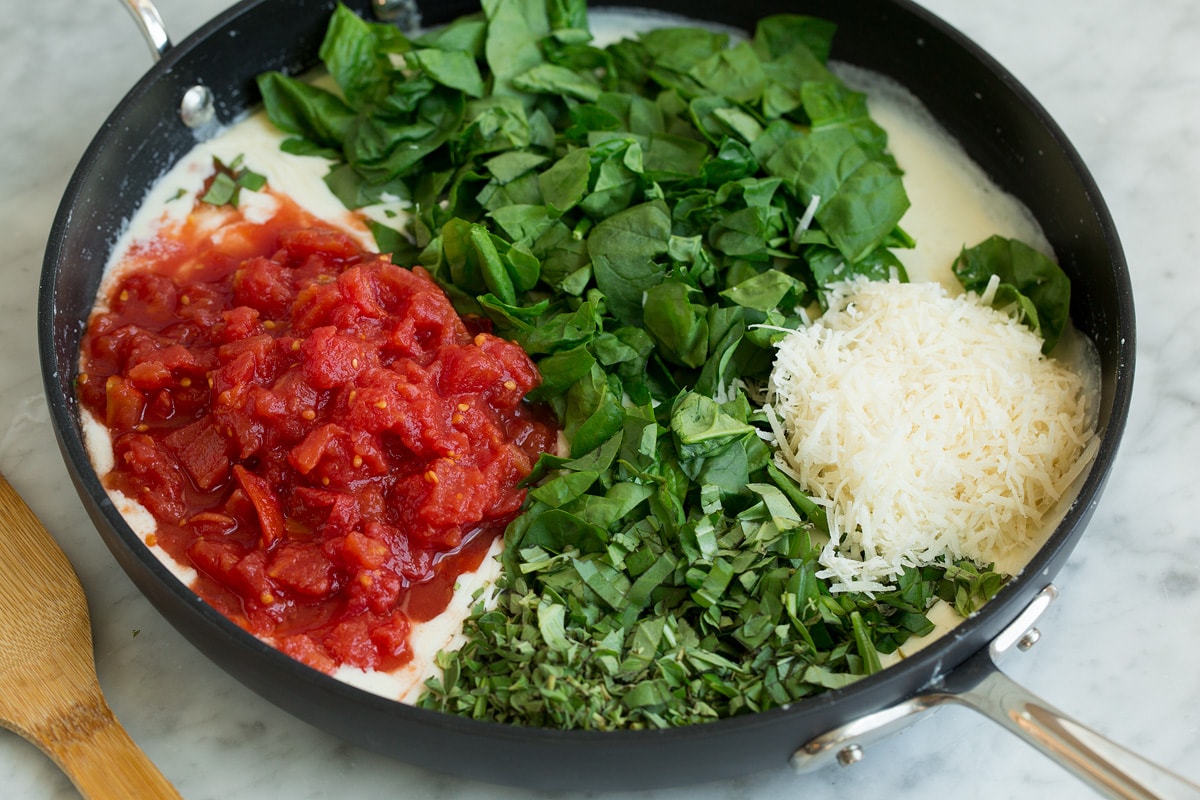 Spinach, tomatoes, fresh herbs and parmesan added to milk mixture in skillet.