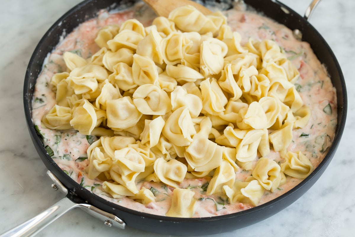 Adding cooked cheese tortellini to pasta sauce