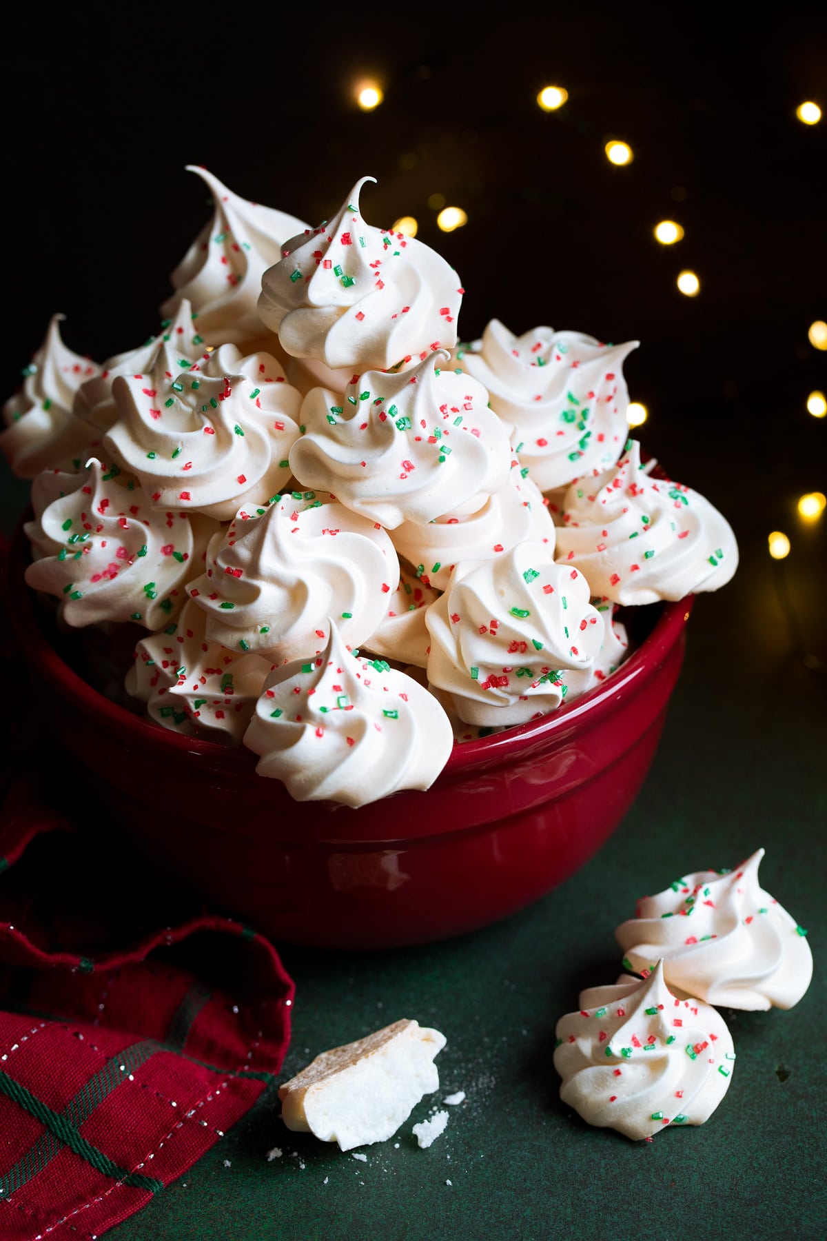 Meringue Cookies decorated with Christmas sprinkles in a red bowl.