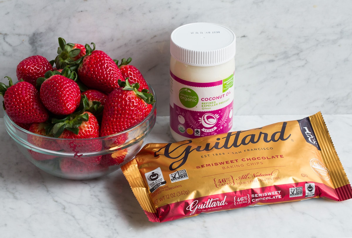 Image showing chocolate chips, coconut oil and fresh strawberries. Which are ingredients needed to make chocolate covered strawberries.