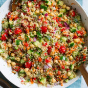 Quinoa Salad in a large serving bowl with wooden tongs on the side.