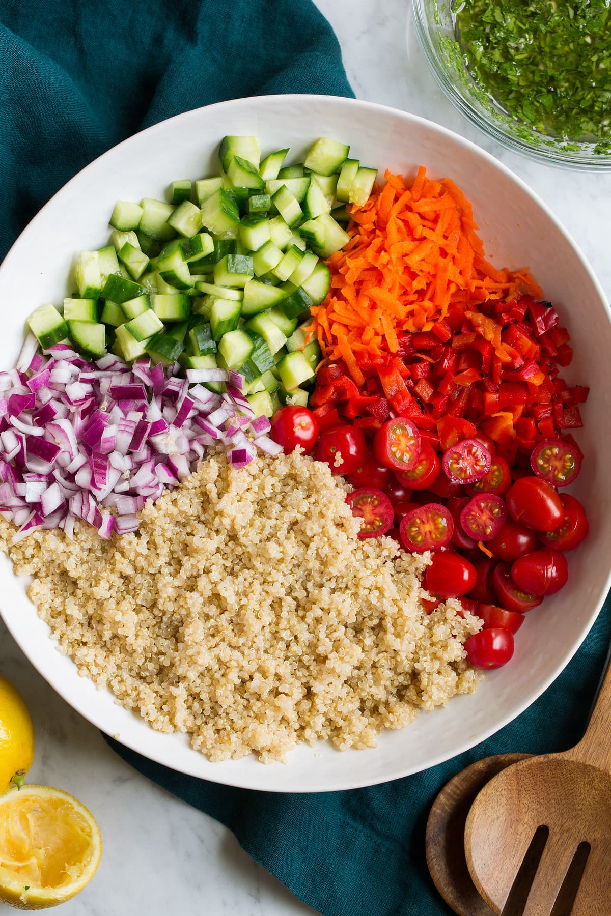 Prepare quinoa salad ingredients in a salad bowl before tossing with dressing.