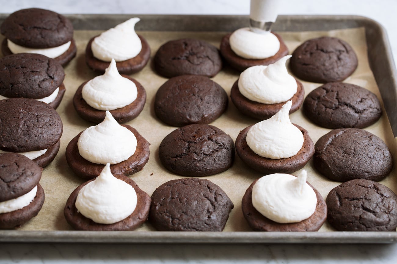 Piping marshmallow cream filling over cookies.