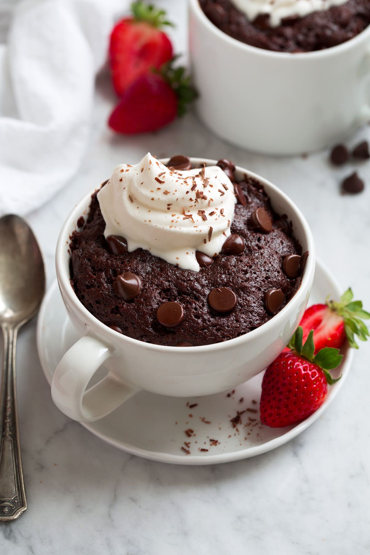 Chocolate Mug Cake with chocolate chips and dollop of whipped cream on top.