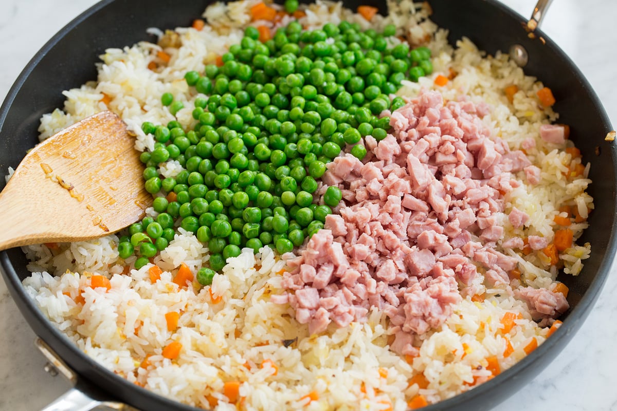 Fried Rice Peas and ham added to fried rice mixture in skillet.