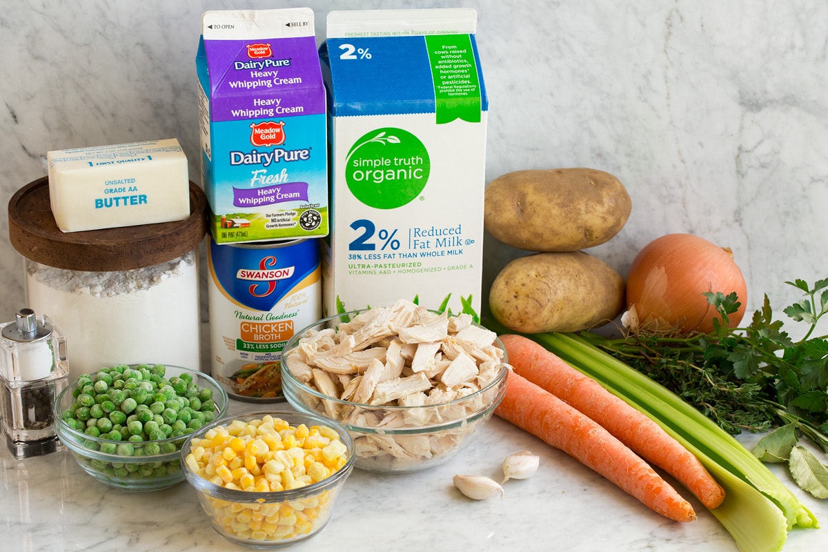 Image showing ingredients needed to make chicken pot pie soup including milk, cream, chicken broth, flour, butter, peas, corn, chicken, carrots, celery, potatoes, onion, garlic and fresh herbs.