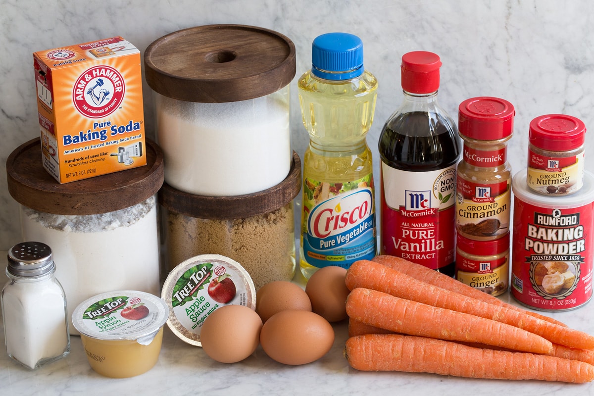 Best Ever Carrot Cake Ingredients that are used to make carrot cake shown here including salt, flour, white sugar, brown sugar, applesauce, baking soda, eggs, carrots, vegetable oil, vanilla, cinnamon, nutmeg, ginger and baking powder.