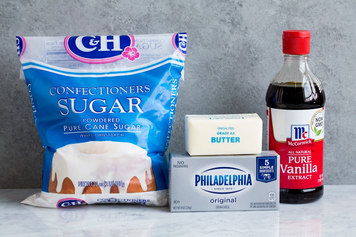 Ingredients used to make cream cheese frosting shown here including powdered sugar, cream cheese, butter and vanilla extract.