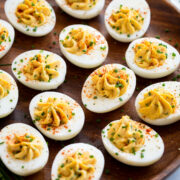 Deviled eggs on a wooden serving platter.