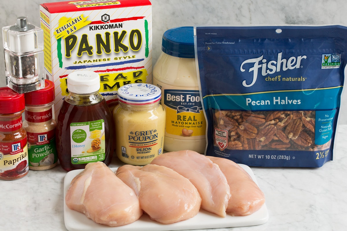 Image of ingredients used to make honey mustard pecan chicken. Shows pecans, chicken breasts, mayonnaise, dijon mustard, panko, paprika, garlic powder, honey, salt and pepper.