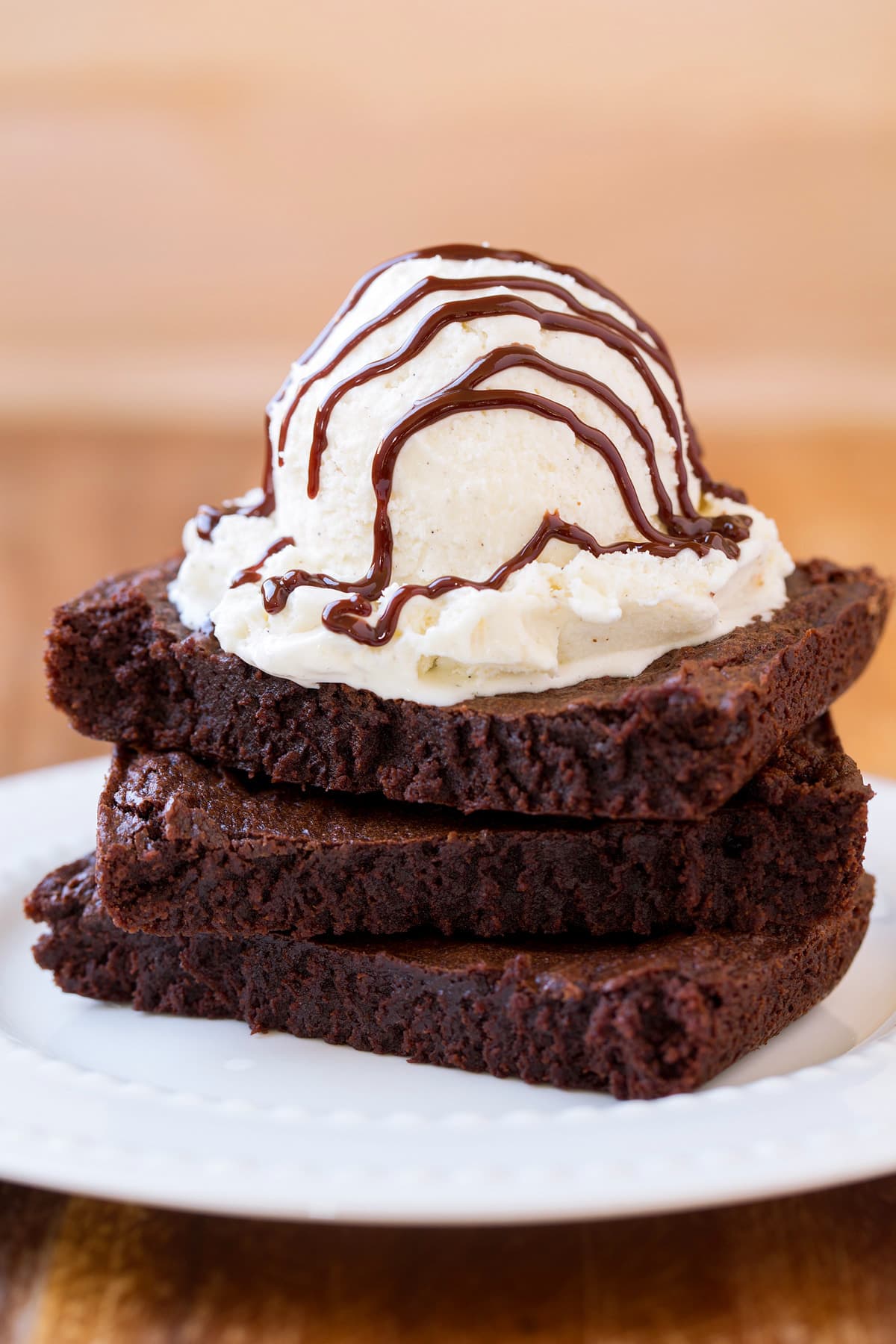 Stack of 3 brownies with ice cream and hot fudge sauce on top.