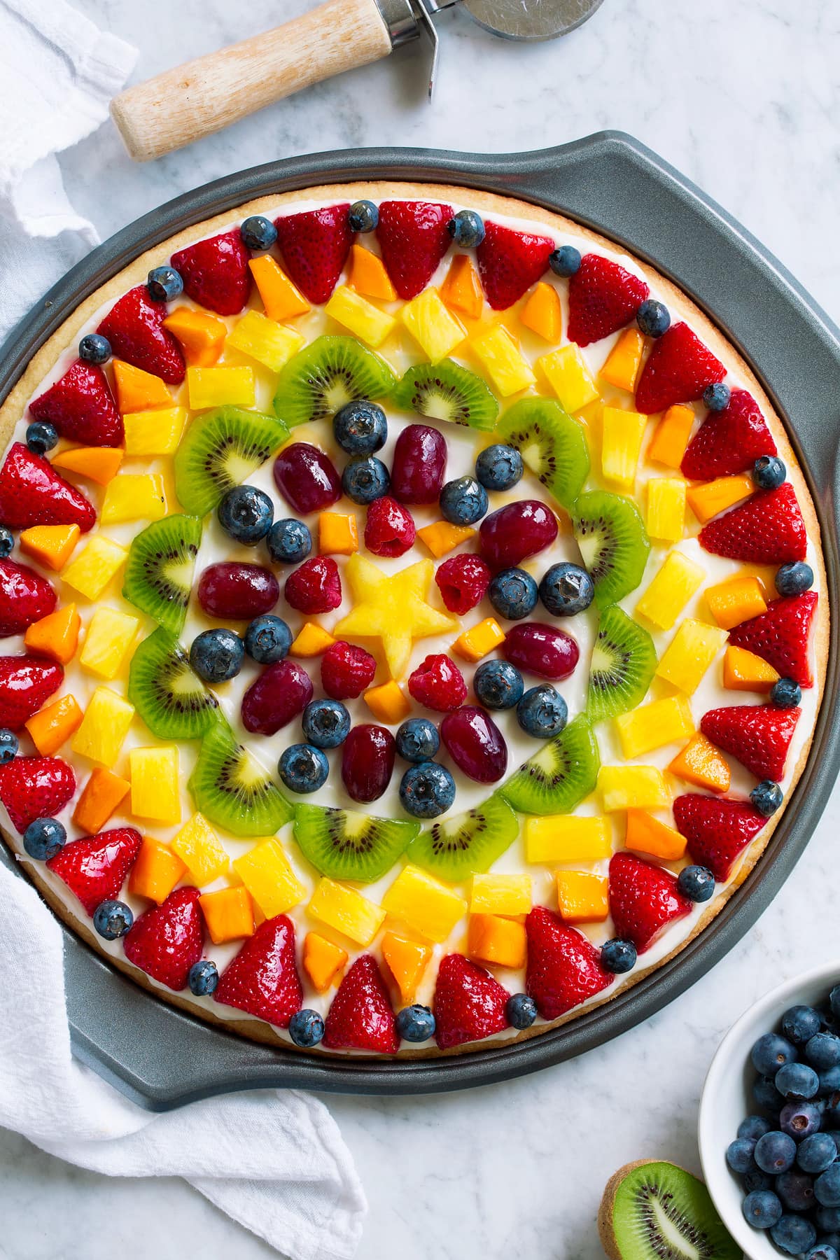 Homemade fruit pizza decorated in a artistic pattern with colorful fresh fruit.
