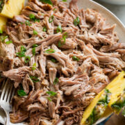 Kalua pork shown in a serving bowl with pineapple and rice to the side.