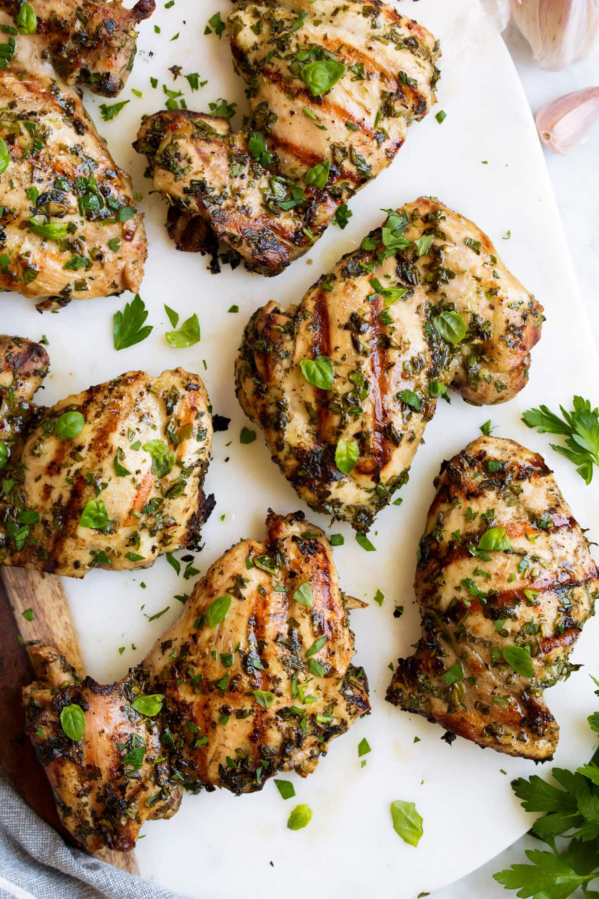 Garlic Herb Grilled Chicken Close up image of grilled chicken with herbs on a white platter.