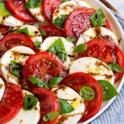 Caprese salad layered in a pretty design shown on a white platter.