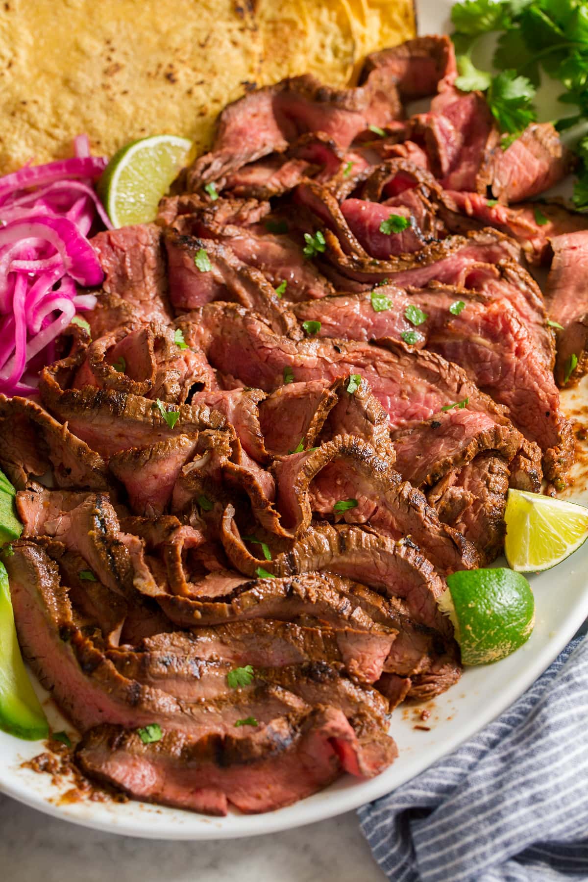 Carne Asada Sliced strips of carne asada shown on a white platter from a side view.