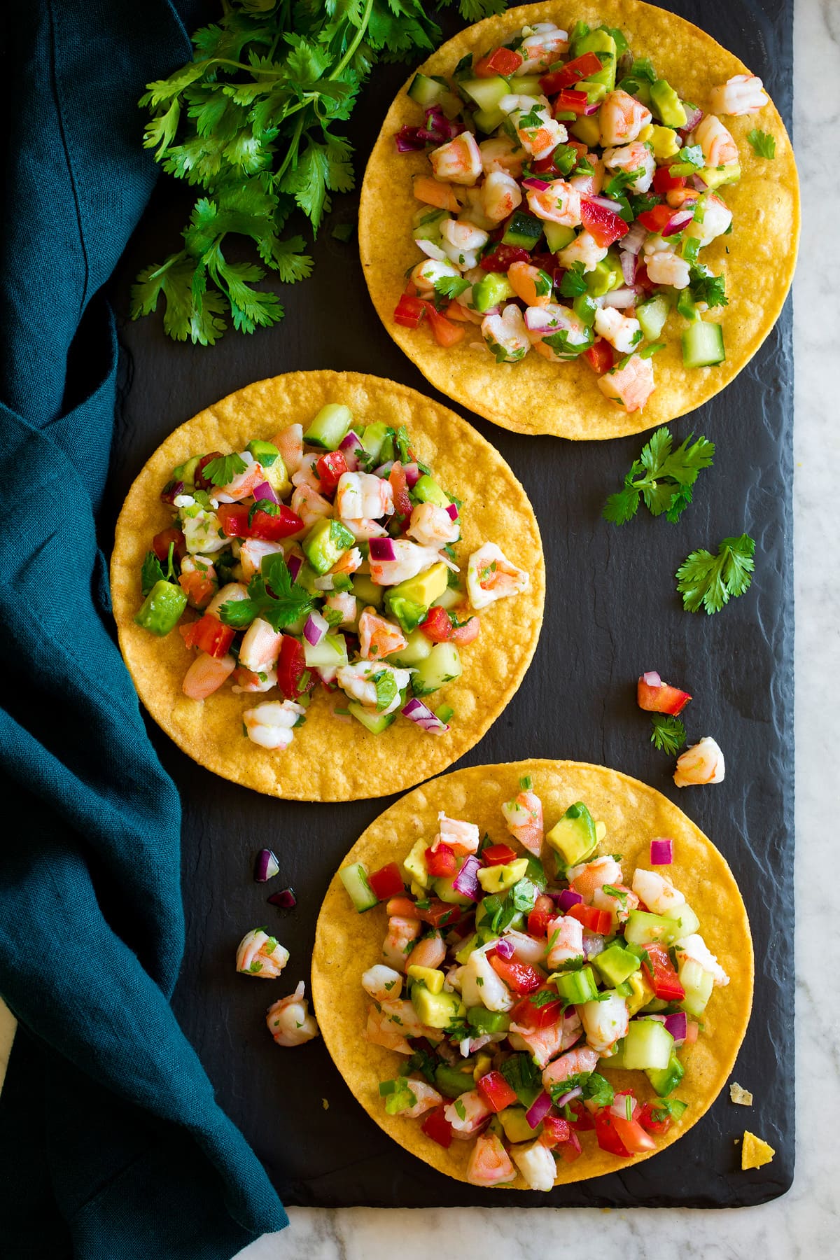 Overhead image of ceviche served on tostada shells resting on a black slate tray.
