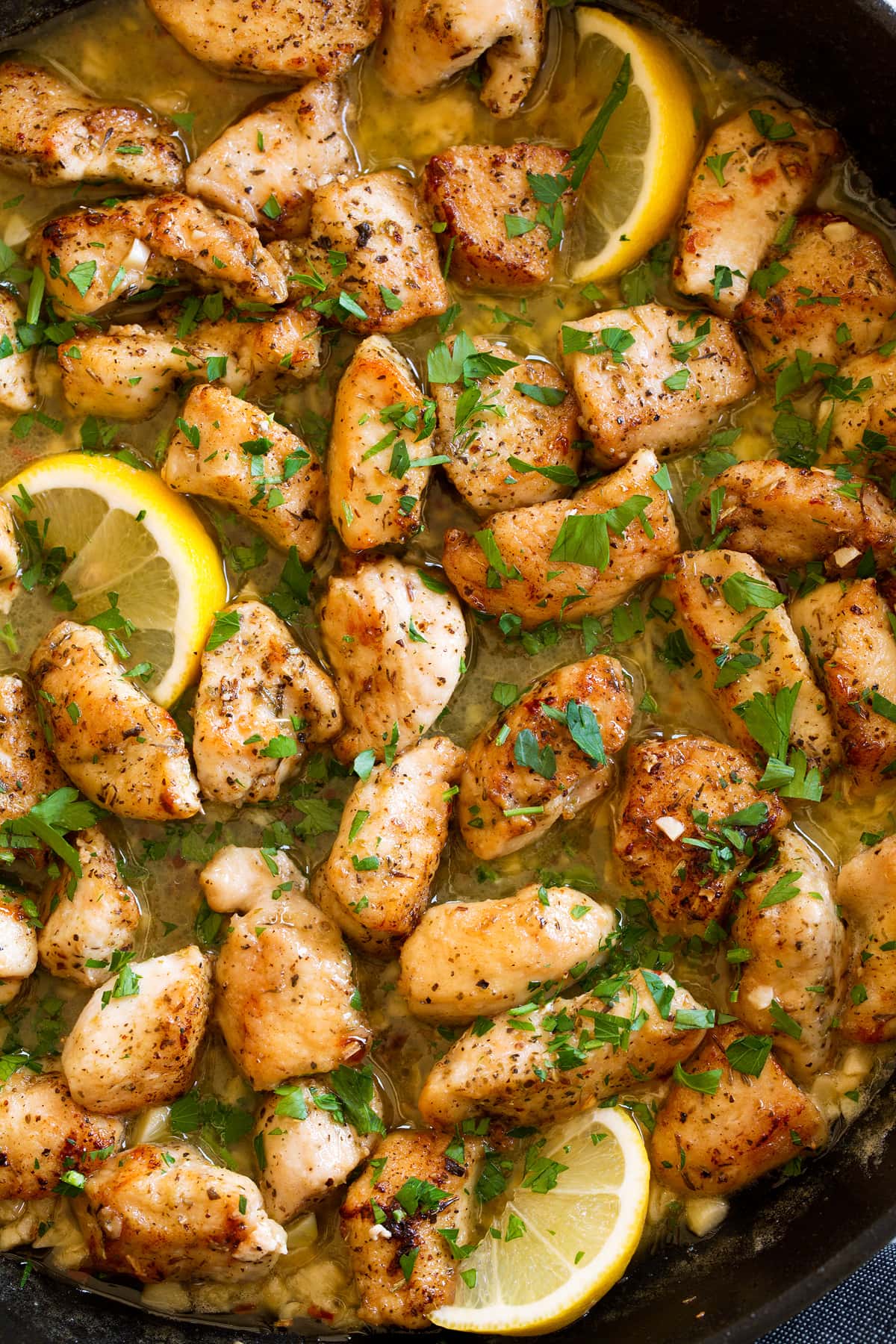Chicken scampi shown overhead in a dark skillet.