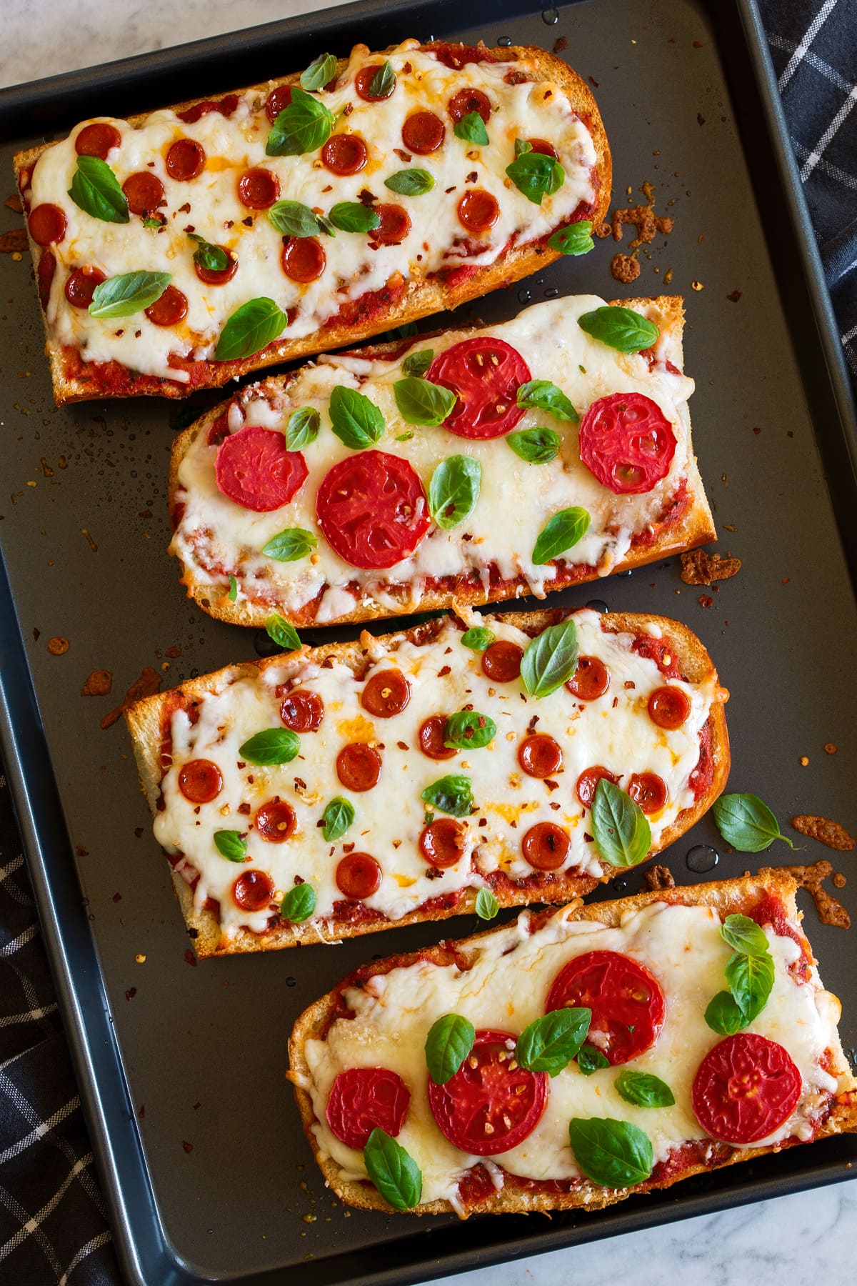 Overhead image of French Bread Pizza on a dark baking sheet.