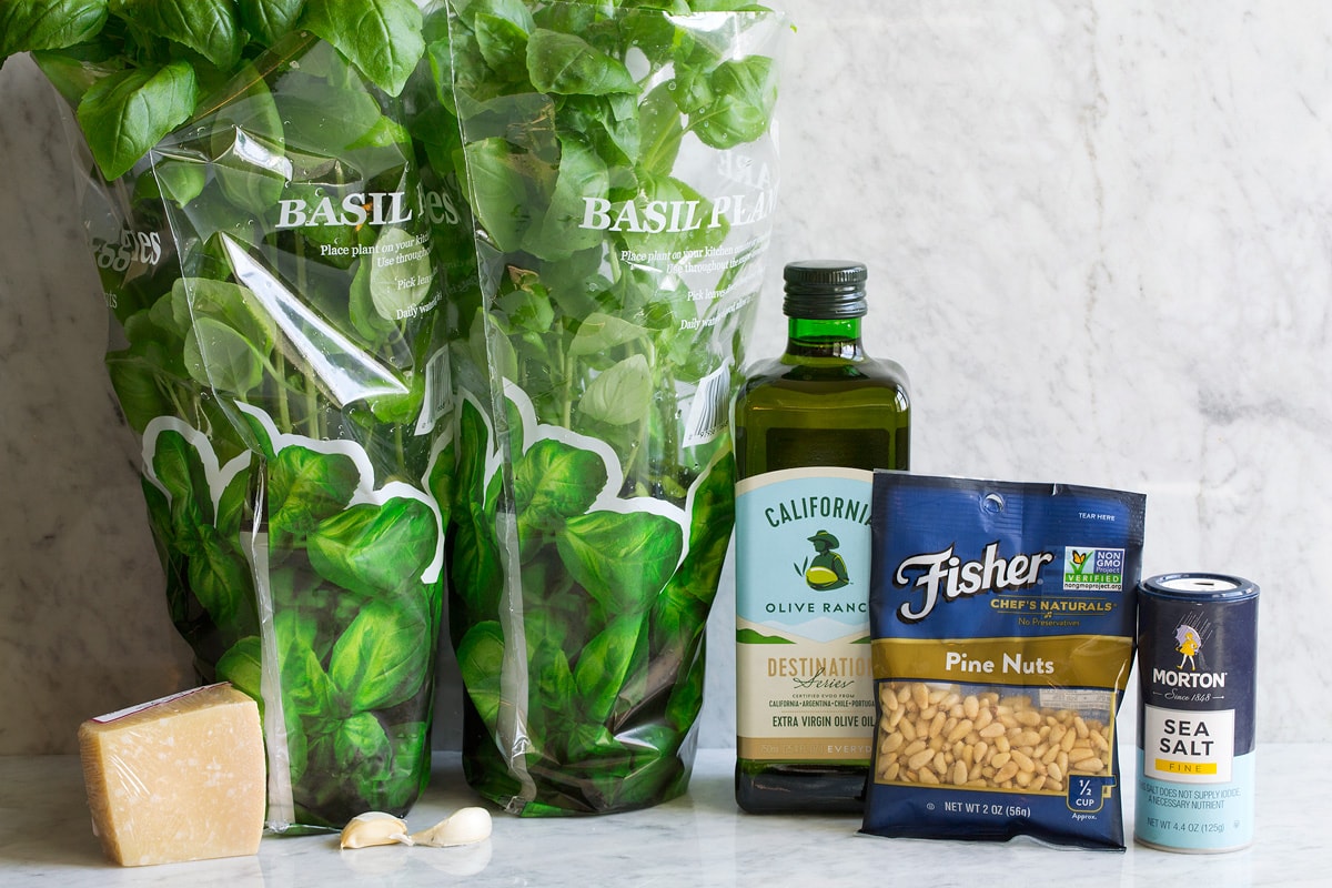 Basil Pesto Image of ingredients used to make pesto shown. Includes fresh basil, parmesan, extra virgin olive oil, pine nuts, garlic and salt.