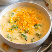 Single serving of broccoli cheese soup in a white bowl with crackers to the side.