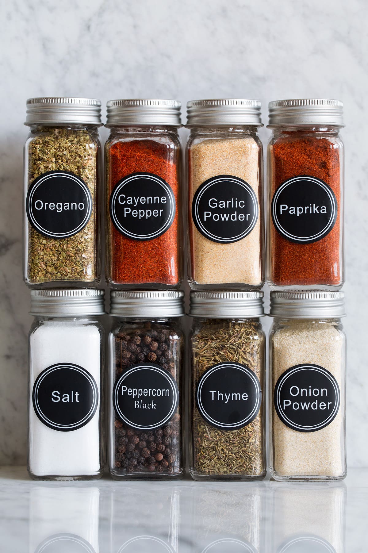 Cajun Seasoning Photo: Eight glass jars of spices that are used to make cajun seasoning shown on a marble surface.