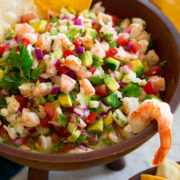 Ceviche in a wooden dip bowl with tortilla chips on the side.