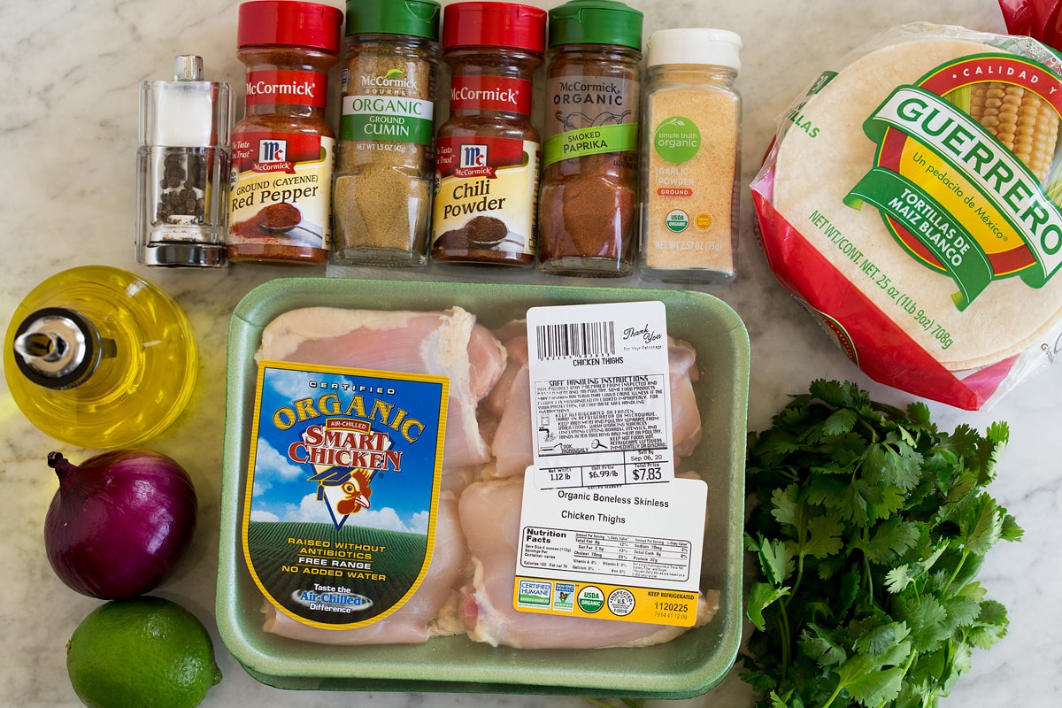 Chicken Tacos Image of ingredients used to make chicken tacos. Includes chicken thighs, chili powder, cumin, cayenne pepper, garlic powder, smokes paprika, corn tortillas, cilantro, red onion, lime and olive oil.