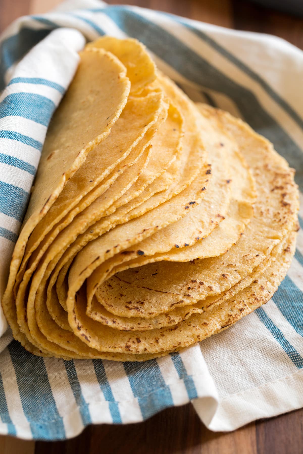 Stack of homemade yellow corn tortillas folded over to show pliability.