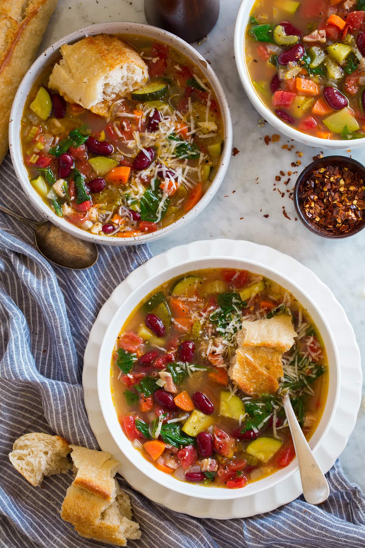 Minestrone Soup Overhead images of two servings of minestrone soup in white bowls set over a marble surface.