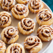 Photo of 12 Mini Cinnamon Rolls shown sitting on white platter over a marble surface.