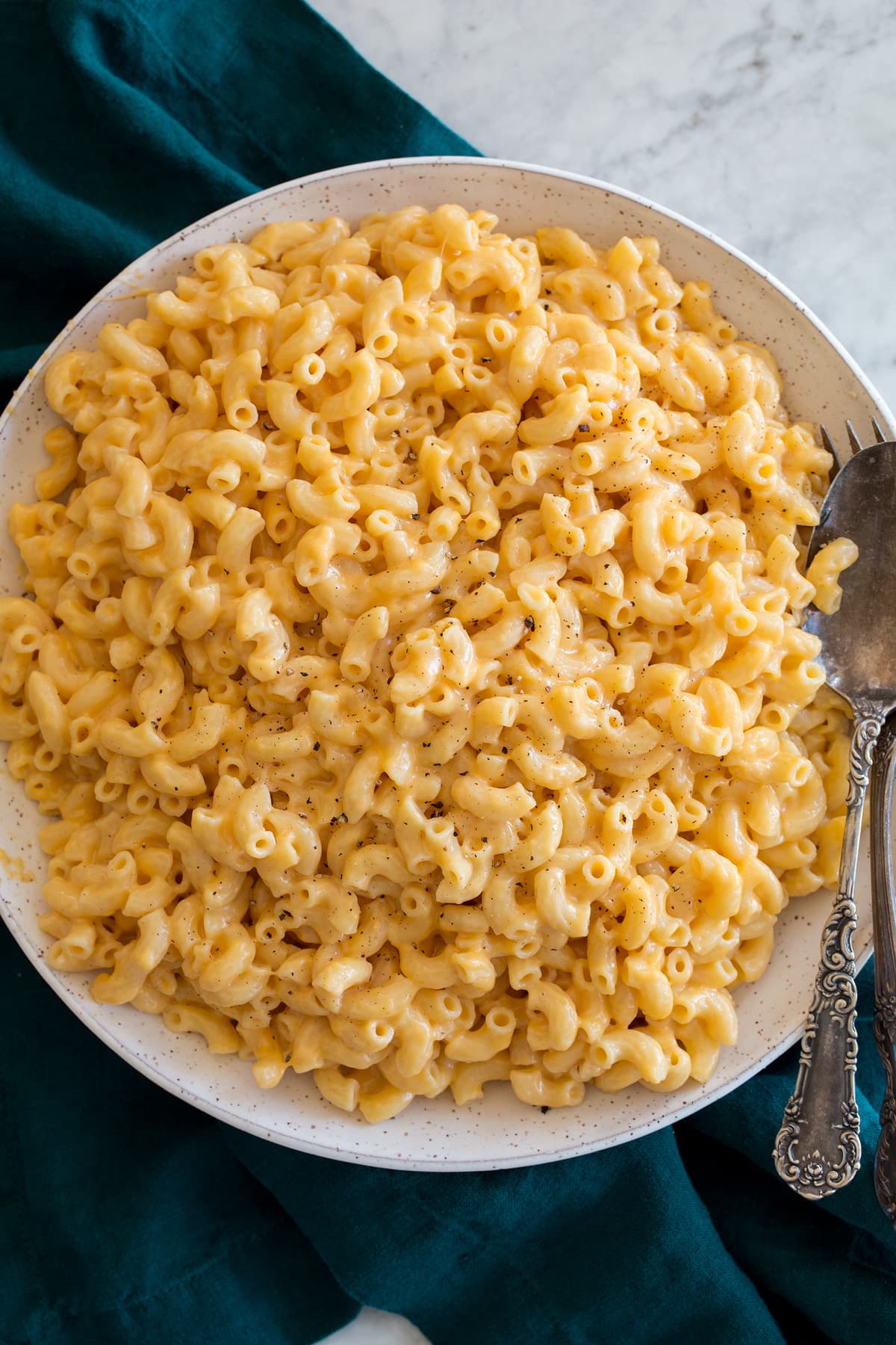 Instant Pot Mac and Cheese Overhead image of Instant Pot Mac and Cheese in a speckled white ceramic bowl set over a turquoise kitchen cloth.