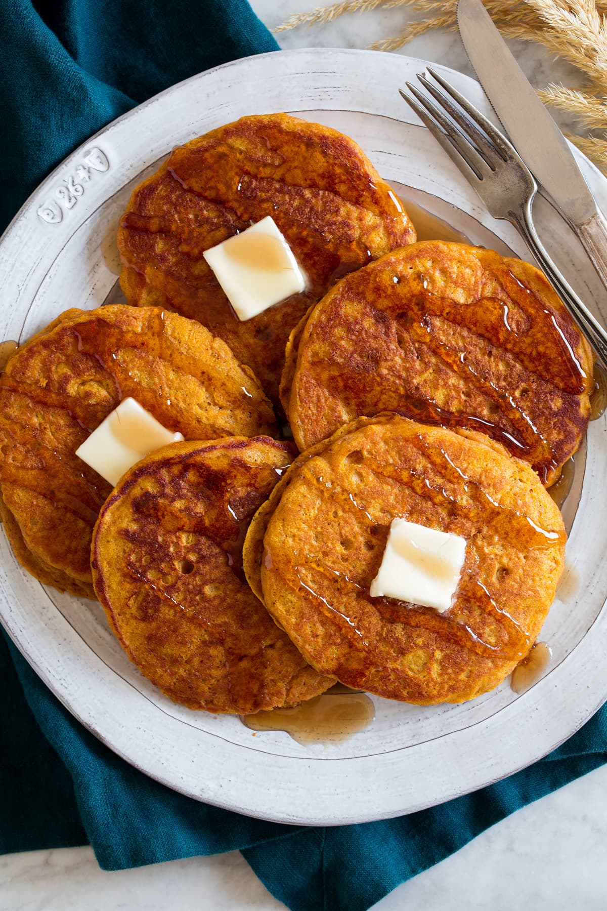 Overhead image of pumpkin pancakes overlapping on a large white plate.
