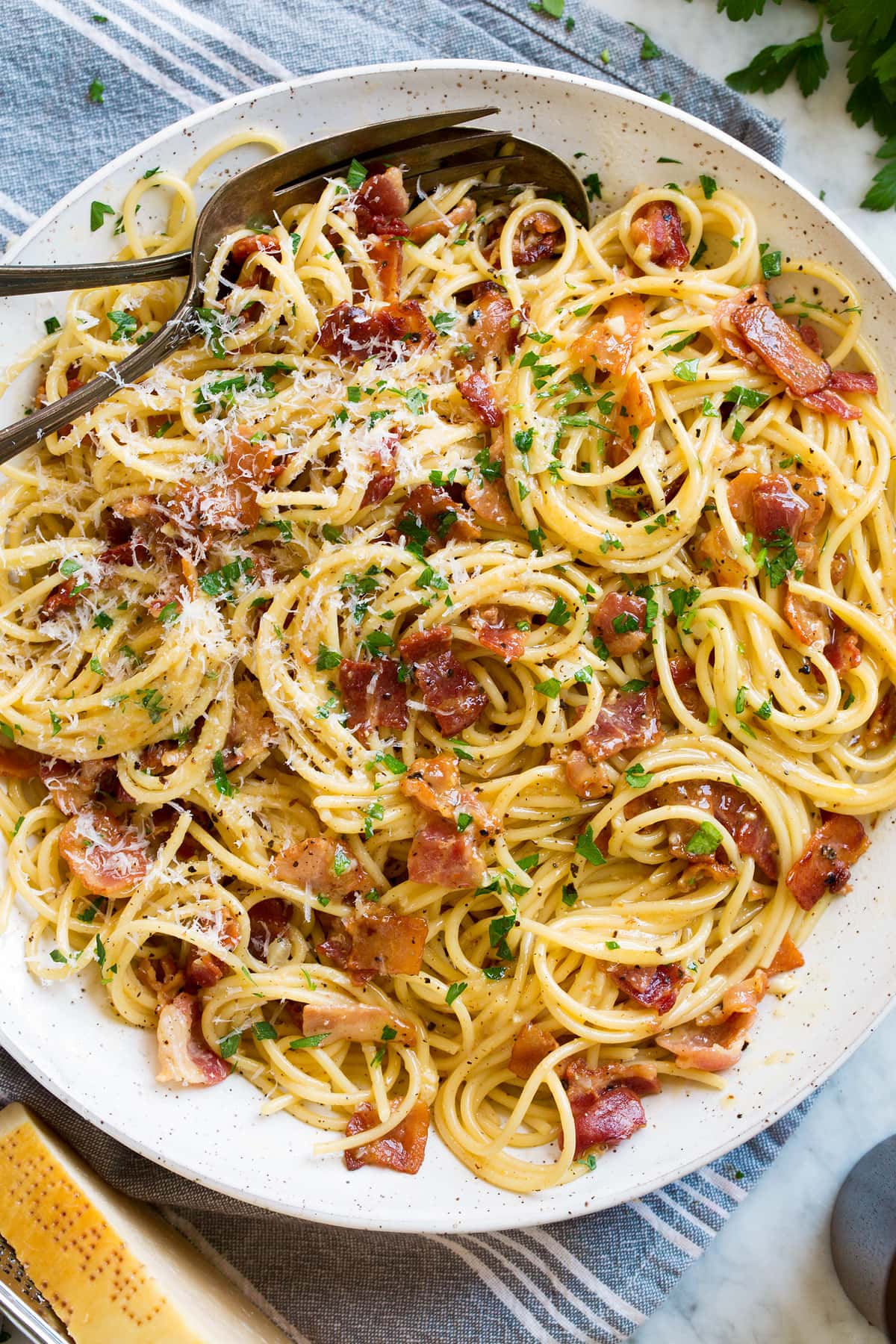 Overhead image of spaghetti carbonara in a large serving bowl set over a grey kitchen cloth.