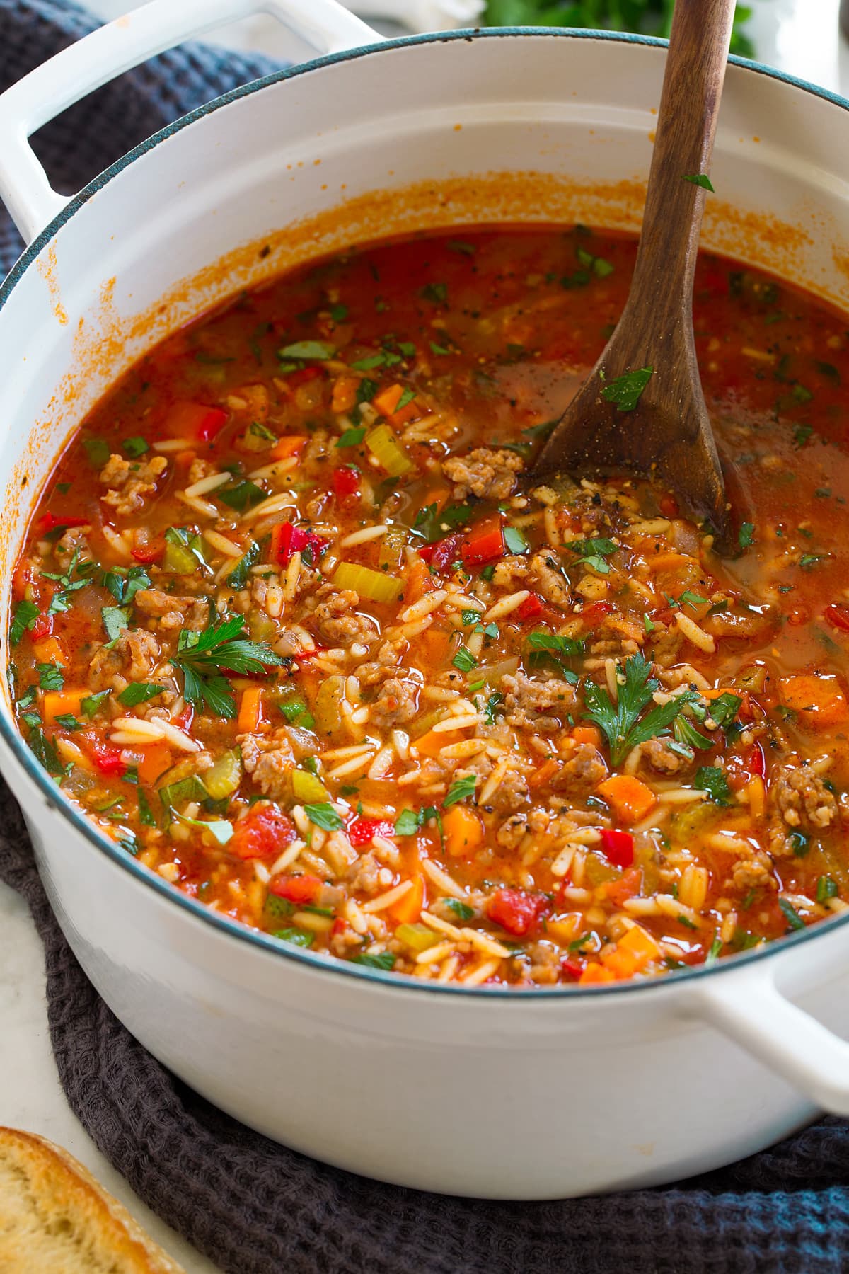 Italian sausage soup shown in a large white pot.