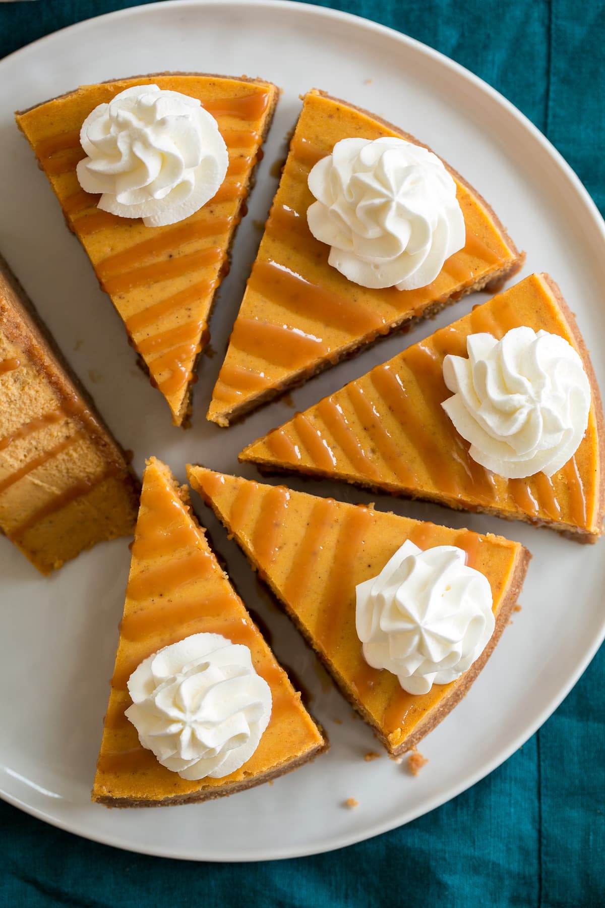 Overhead image of six slices of pumpkin cheesecake on a white serving platter.