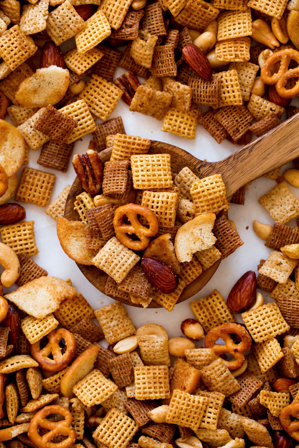 Chex Mix Wood spoon full of Chex Mix shown close up.