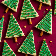 Triangular decorated Christmas tree cookies shown on a red surface.